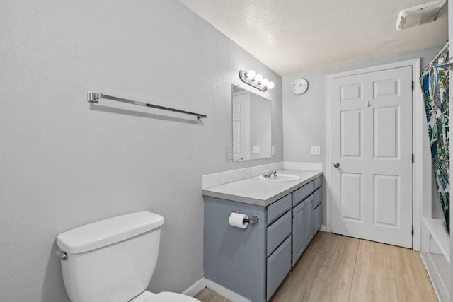 full bathroom with vanity, a textured ceiling, shower / bathtub combination with curtain, hardwood / wood-style floors, and toilet