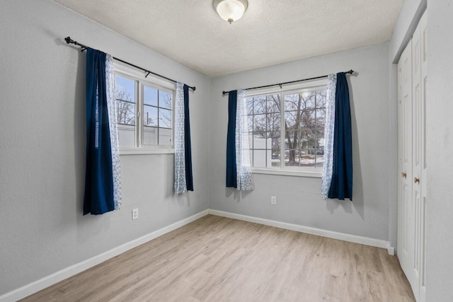 empty room featuring plenty of natural light, light hardwood / wood-style floors, and a textured ceiling