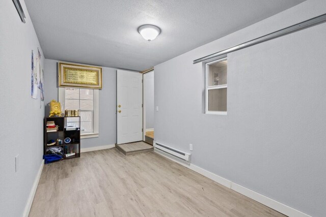 interior space featuring light hardwood / wood-style flooring, a baseboard radiator, and a textured ceiling