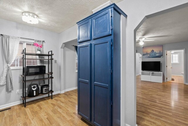 kitchen with blue cabinetry, ceiling fan, light hardwood / wood-style flooring, and a textured ceiling