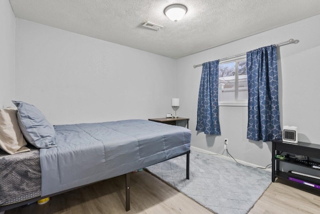 bedroom with a textured ceiling and light wood-type flooring