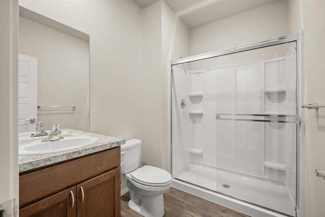 bathroom with hardwood / wood-style flooring, vanity, toilet, and walk in shower