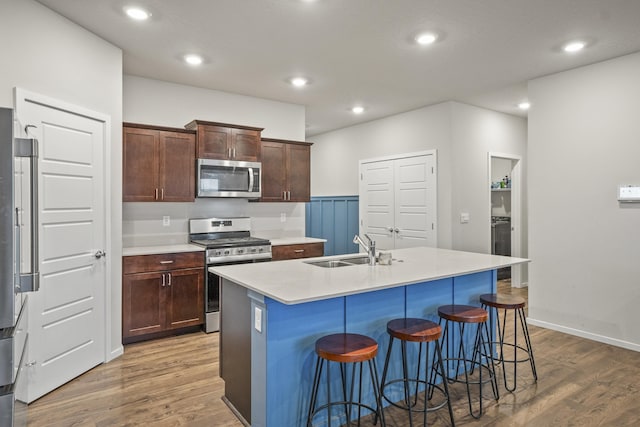 kitchen featuring appliances with stainless steel finishes, hardwood / wood-style flooring, a kitchen island with sink, and sink