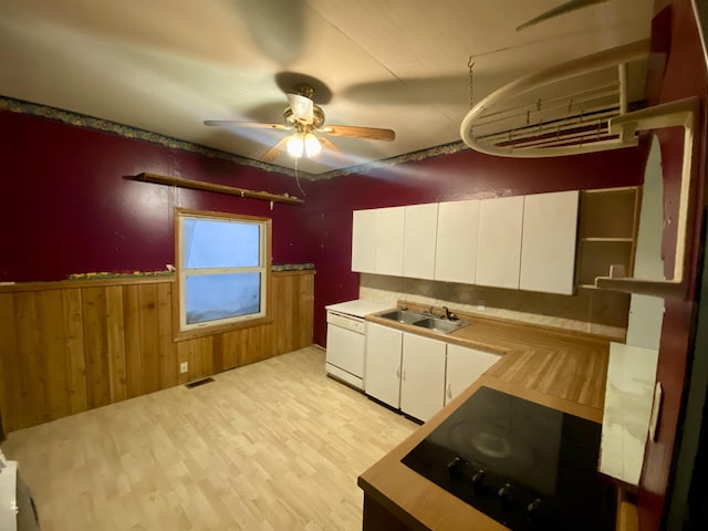 kitchen with white cabinetry, sink, wood walls, black electric stovetop, and light wood-type flooring