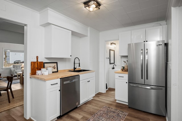 kitchen with white cabinets, sink, appliances with stainless steel finishes, and wooden counters