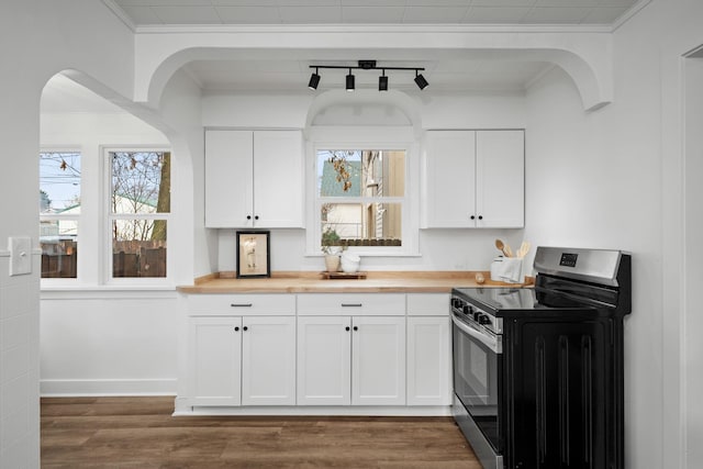 kitchen featuring butcher block counters, crown molding, rail lighting, stainless steel stove, and white cabinetry