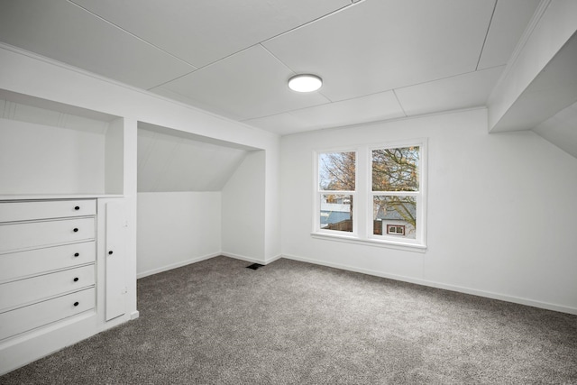 bonus room with dark colored carpet and vaulted ceiling