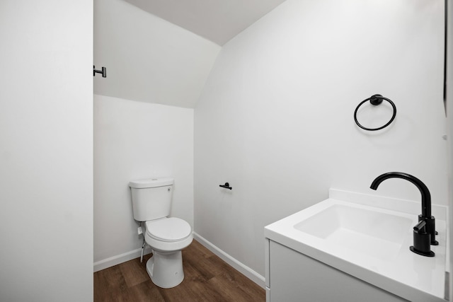 bathroom with hardwood / wood-style flooring, vanity, lofted ceiling, and toilet