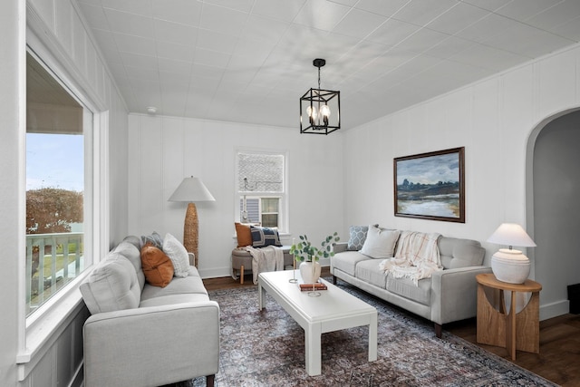 living room featuring a wealth of natural light, dark hardwood / wood-style flooring, and an inviting chandelier