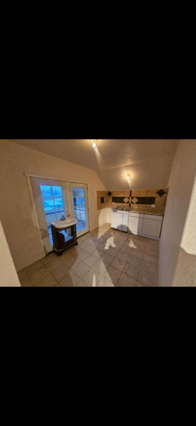 hallway with light tile patterned floors and lofted ceiling