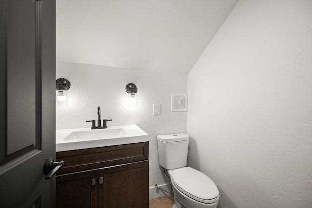 bathroom with vanity, toilet, and lofted ceiling