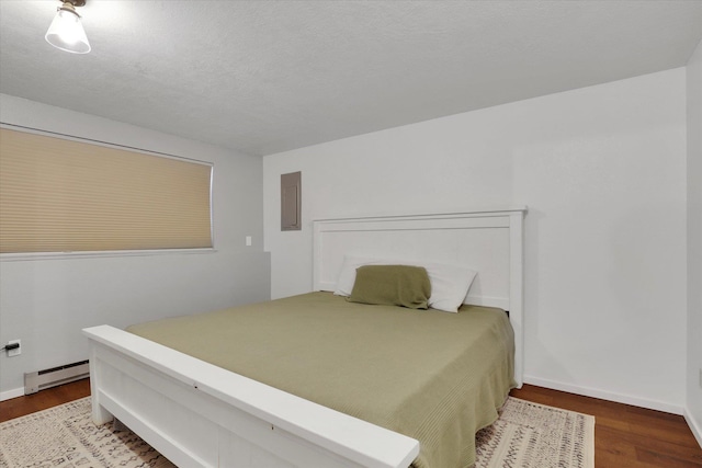 bedroom featuring hardwood / wood-style floors, baseboard heating, and electric panel