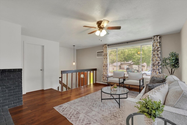 living room with ceiling fan, wood-type flooring, a textured ceiling, and an AC wall unit