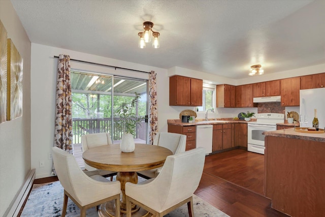 dining space featuring baseboard heating, sink, dark wood-type flooring, and a textured ceiling