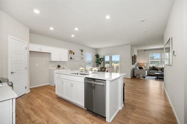 kitchen with white cabinetry, stainless steel dishwasher, a kitchen island with sink, and sink