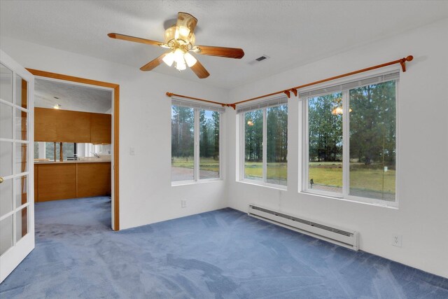 unfurnished sunroom featuring ceiling fan and a baseboard radiator