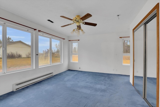 interior space featuring a closet, dark carpet, ceiling fan, and a baseboard heating unit