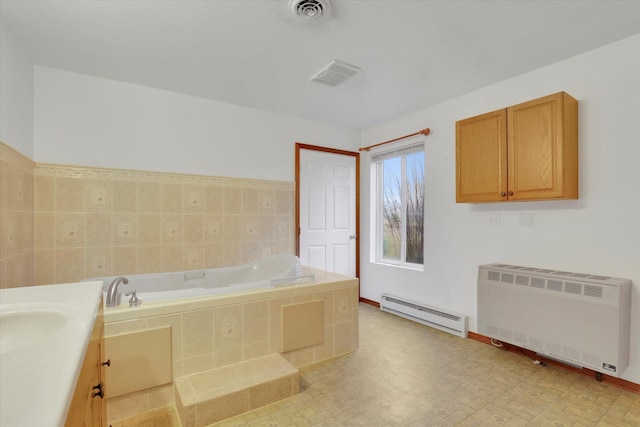 bathroom featuring vanity, tiled tub, radiator, and a baseboard radiator