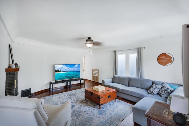 living room with ceiling fan, wood-type flooring, and a brick fireplace