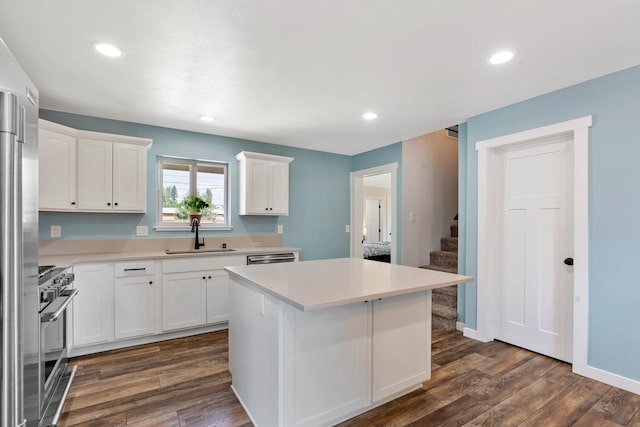 kitchen featuring stainless steel appliances, dark wood-type flooring, sink, white cabinets, and a center island