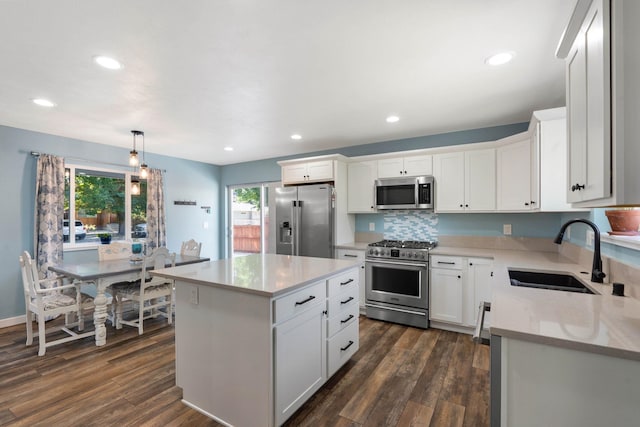 kitchen with sink, hanging light fixtures, white cabinets, a kitchen island, and appliances with stainless steel finishes