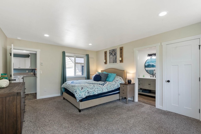 bedroom with carpet flooring, ensuite bath, and sink