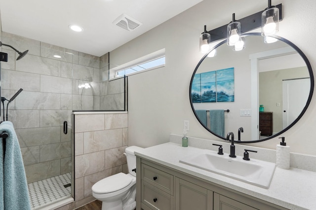 bathroom featuring vanity, a shower with shower door, and toilet