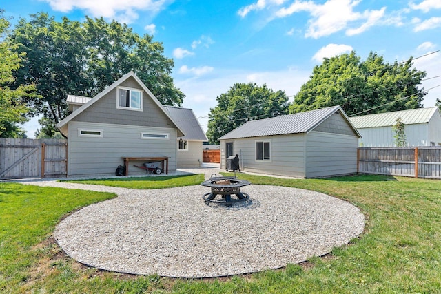 back of property with a lawn, an outdoor structure, and an outdoor fire pit