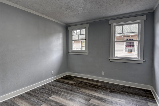 empty room featuring dark hardwood / wood-style flooring, ornamental molding, a wealth of natural light, and a textured ceiling