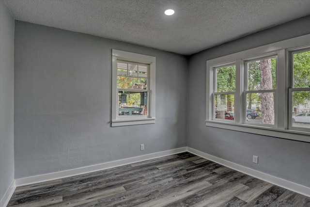 spare room featuring dark hardwood / wood-style flooring and a textured ceiling