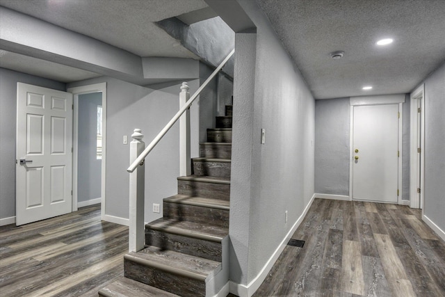 stairs with hardwood / wood-style flooring and a textured ceiling