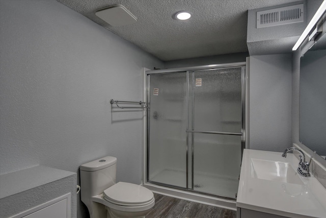 bathroom featuring toilet, a textured ceiling, vanity, a shower with door, and hardwood / wood-style flooring