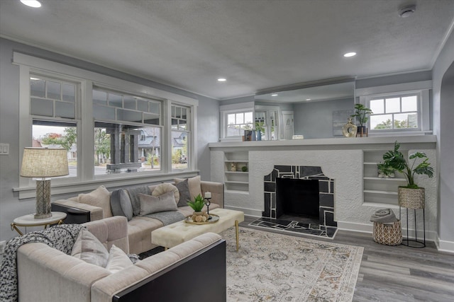 living room featuring ornamental molding, wood-type flooring, a high end fireplace, and a textured ceiling