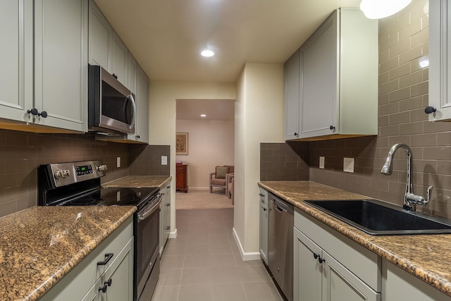 kitchen featuring sink, stone countertops, decorative backsplash, light tile patterned floors, and appliances with stainless steel finishes