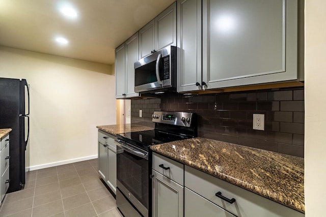 kitchen with decorative backsplash, appliances with stainless steel finishes, dark stone counters, and light tile patterned flooring