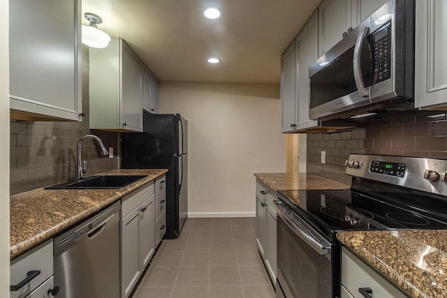 kitchen with backsplash, dark stone counters, stainless steel appliances, sink, and light tile patterned floors