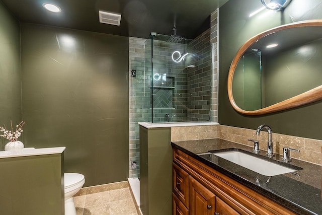 bathroom featuring tile patterned floors, toilet, vanity, and tiled shower