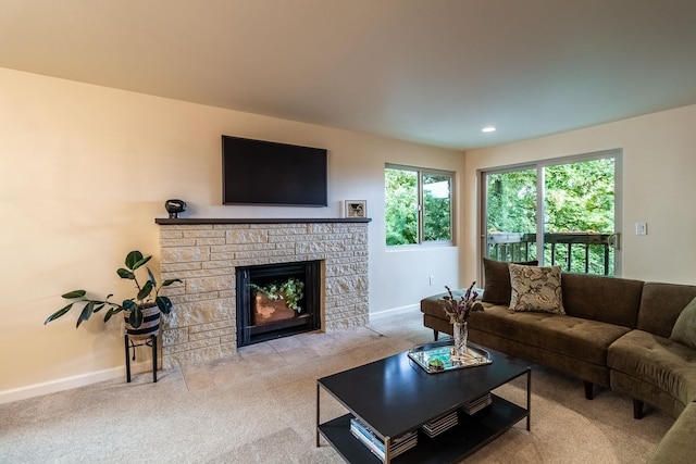 carpeted living room with a stone fireplace