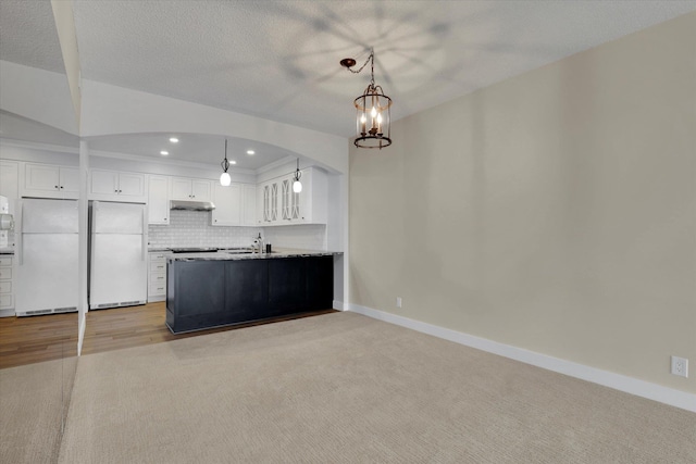 kitchen featuring backsplash, white cabinetry, white fridge, and a notable chandelier