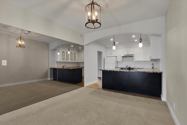 kitchen with tasteful backsplash, white refrigerator, decorative light fixtures, an inviting chandelier, and white cabinetry