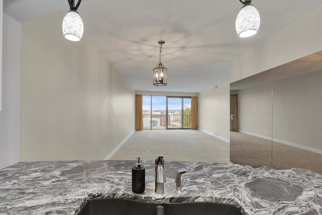 interior space featuring sink, hanging light fixtures, an inviting chandelier, a textured ceiling, and carpet