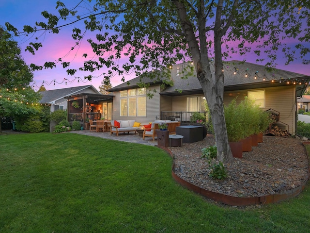 back house at dusk featuring outdoor lounge area, a yard, and a patio