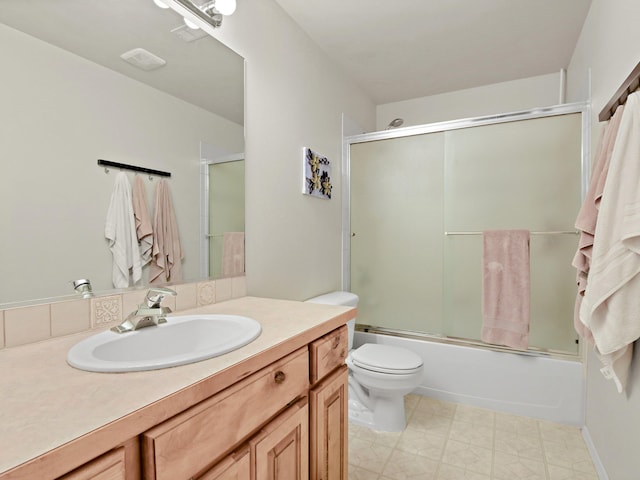 full bathroom featuring vanity, combined bath / shower with glass door, and toilet