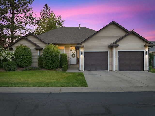 single story home featuring a garage and a lawn