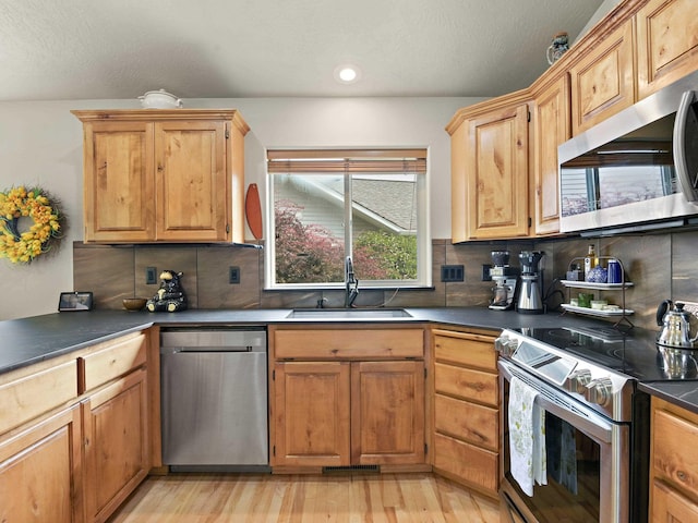 kitchen with decorative backsplash, sink, stainless steel appliances, and light wood-type flooring