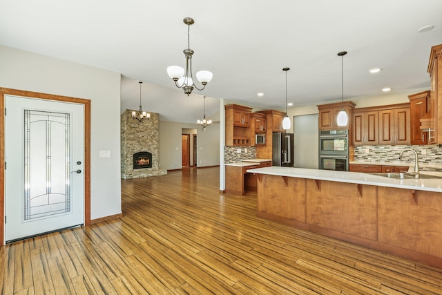 kitchen with sink, kitchen peninsula, a breakfast bar area, decorative backsplash, and appliances with stainless steel finishes