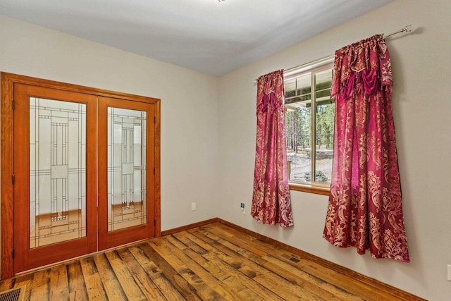 empty room with french doors and hardwood / wood-style flooring