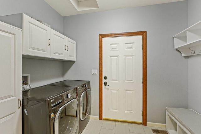 clothes washing area with cabinets and independent washer and dryer