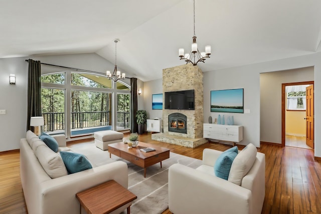 living room featuring a notable chandelier, a stone fireplace, lofted ceiling, and light hardwood / wood-style flooring