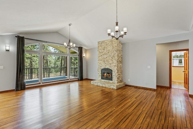 unfurnished living room featuring hardwood / wood-style flooring, a stone fireplace, lofted ceiling, and an inviting chandelier